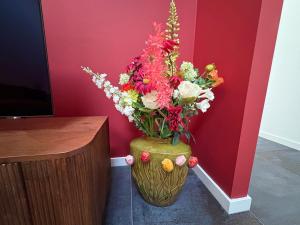 eine Vase voller Blumen neben einer Wand in der Unterkunft Sfeervolle villa met sauna aan de rand van het bos in Putten