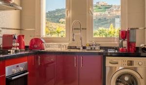 a kitchen with red cabinets and a sink and a window at Mnar Castle in Tangier