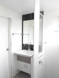 Baño blanco con lavabo y espejo en Coral Point Lodge en Shute Harbour