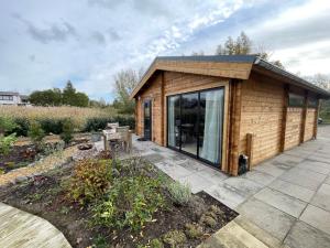 een kleine houten hut met een terras in een tuin bij NIEUW Bed & Breakfast Puur Poortugaal in Poortugaal