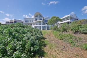 Beachfront, Sea Views, WiFi, Fireplace, 1-Min Walk في Cape Town: مبنى على الشاطئ مع شجيرات أمامه