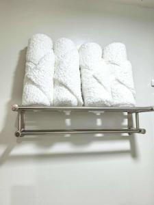 un estante de metal con cuatro toallas blancas encima en Cozy Studio with Balcony in Palawan Smart Lock, Near Airport, Netflix, Free Wifi, en Bancaobancao