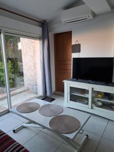 a living room with a tv and a table at Studio sur les hauteurs de La Ciotat vue mer in La Ciotat