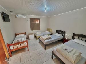 a room with two beds and a couch and a table at Motel e Pousada Ponto G in Não Me Toques