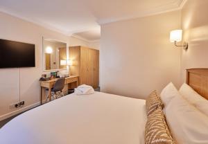 a hotel room with a large bed and a desk at Thistle London Heathrow Terminal 5 in Hillingdon