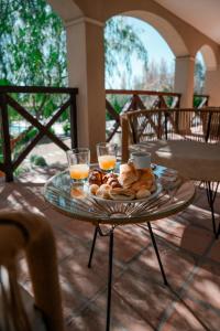 a table with a plate of food and two glasses of orange juice at El Colonial Departamentos in Cafayate