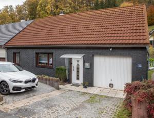 una casa con un coche blanco aparcado delante de ella en Ferienhaus im Pochwerksgrund in Suhl Goldlauter im Thüringer Wald, en Suhl