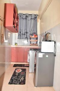 Elle comprend une petite cuisine équipée de placards rouges et d'un réfrigérateur. dans l'établissement Comfy one bedroom Eldoret town, à Eldoret
