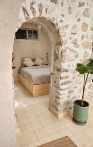 une chambre avec un lit dans un mur de pierre dans l'établissement DAR NAYA - Ghazoua - Essaouira, à Al Ghar