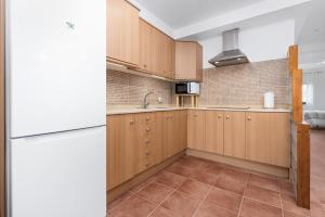 a kitchen with wooden cabinets and a white refrigerator at Home2Book Sunny Terrace Getaway Puerto Lajas in Puerto de las Lajas