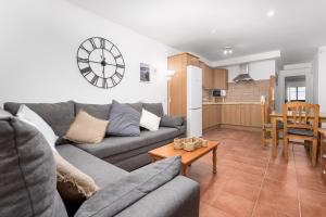 a living room with a couch and a clock on the wall at Home2Book Sunny Terrace Getaway Puerto Lajas in Puerto de las Lajas