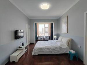 a bedroom with a white bed and a television at Central Street River View Apartment in Harbin