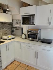 a kitchen with white cabinets and a microwave at Slakkepas 52 in Dwarskersbos