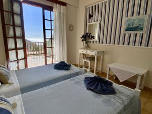 two beds in a room with a view of the ocean at Saint George Hotel in Rodakino