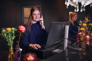 uma mulher a falar ao telefone numa secretária com um computador em Van der Valk hotel Harderwijk em Harderwijk