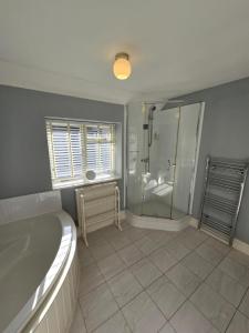 a large bathroom with a tub and a shower at Grebe Cottage in Isle of Wight