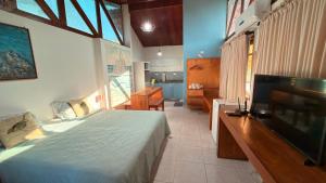 une chambre avec un lit et une télévision à écran plat dans l'établissement Flat Siriguela, à Fernando de Noronha