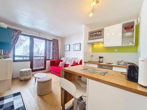 eine Küche und ein Wohnzimmer mit einem roten Sofa in der Unterkunft Studio cozy à La Daille, accès direct pistes, balcon, ascenseur - FR-1-518-158 in Val dʼIsère