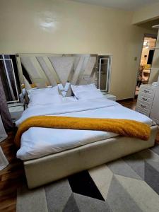 内罗毕Cozy 2-Bedroom的一张配有白色床单和橙色毯子的大床 更多16张照片