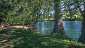 a river with trees and a path next to the water at Humming Bird Haven in Utopia