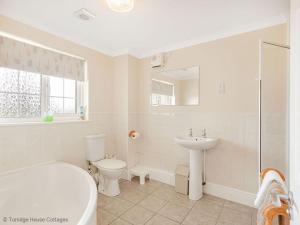 a bathroom with a tub and a toilet and a sink at Hen Cottage in Little Torrington +5 photos