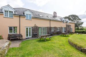 ein Haus mit Picknicktischen im Hof in der Unterkunft Hen Cottage in Little Torrington
