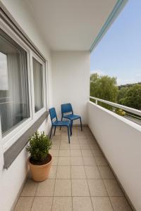 zwei blaue Stühle auf einem Balkon mit Fenster in der Unterkunft SUNNYHOME Monteurwohnungen und Apartments in Weiden in Weiden