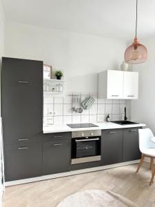 a kitchen with gray cabinets and white appliances at Self Check-in Haus - 15min zum Hbf und Messe in Düsseldorf