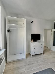 a white room with a tv and a white dresser at Self Check-in Haus - 15min zum Hbf und Messe in Düsseldorf