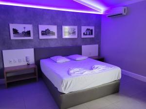 a bedroom with a bed with purple lights on it at Motel Daponti in Alegrete