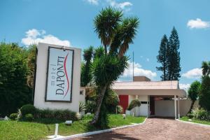 a sign in front of a building with a palm tree at Motel Daponti in Alegrete