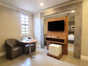 a room with a table and a tv and a bed at Motel Daponti in Alegrete