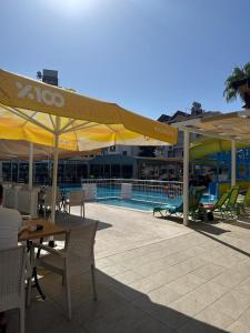 a patio with tables and umbrellas next to a swimming pool at Saygılı Beach Hotel in Side