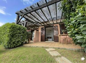 eine Terrasse mit einem Tisch und Stühlen unter einem Holzdach in der Unterkunft 8 ARBOUSIERS VILLA 16 in Bonifacio