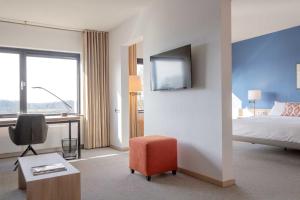 a hotel room with a bed and a desk and a tv at Hotel De Ruwenberg Den Bosch - Sint Michielsgestel in Den Bosch
