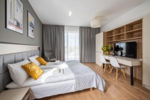 a bedroom with a bed and a desk and a television at Aparthotel City Break Wolska by INA in Warsaw
