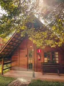 un bâtiment en bois avec un banc devant lui dans l'établissement Hotel Pousada Cata Branca, à Itabirito