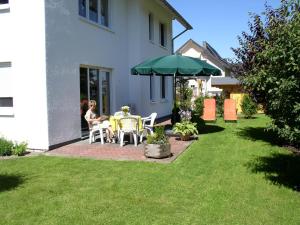 a woman sitting at a table under a green umbrella at Ferienhaus Wiese in Bruchhausen +5 photos