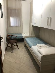 a bedroom with two beds and a chair and a window at Casa Donatella a Isola in Isola delle Femmine