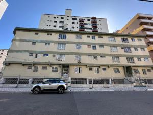 un coche aparcado delante de un gran edificio en Guilhermina 250m do Mar! Com garagem!, en Praia Grande