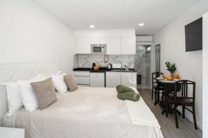 a white bedroom with a large bed and a kitchen at OurMadeira - TerraceSea Caldeirão Verde in Ribeira Brava