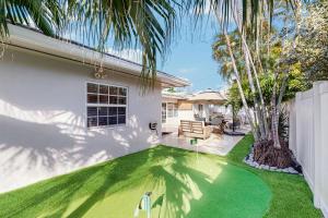een huis met een tuin met een putting green bij Once Upon a Beach Time in Pompano Beach