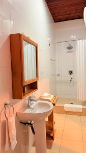 a white bathroom with a sink and a shower at Coconut Grove Beach Resort in Elmina