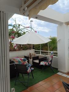 a patio with an umbrella and two chairs and a couch at Apartamento Residencial mojacar in Mojácar