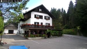 a large white building with flowers in a parking lot at apartma fortuna kmečki hram in Idrija
