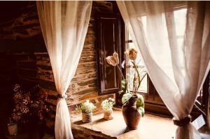 een raam met gordijnen en bloemen op een vensterbank bij Casa Da Fragua in Samos