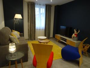 a living room with a couch and a tv at Le gîte de Marina in Figeac