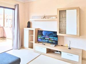 ein Wohnzimmer mit einem Fernseher auf einem hölzernen Entertainment-Center in der Unterkunft Casa Marley – Balcòn Del Mar in Costa Del Silencio