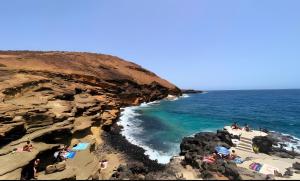 eine Gruppe von Menschen an einem Strand in der Nähe des Ozeans in der Unterkunft Casa Marley – Balcòn Del Mar in Costa Del Silencio