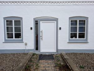 a white house with a white door and two windows at Stadtnah an der Förde 5501 in Flensburg